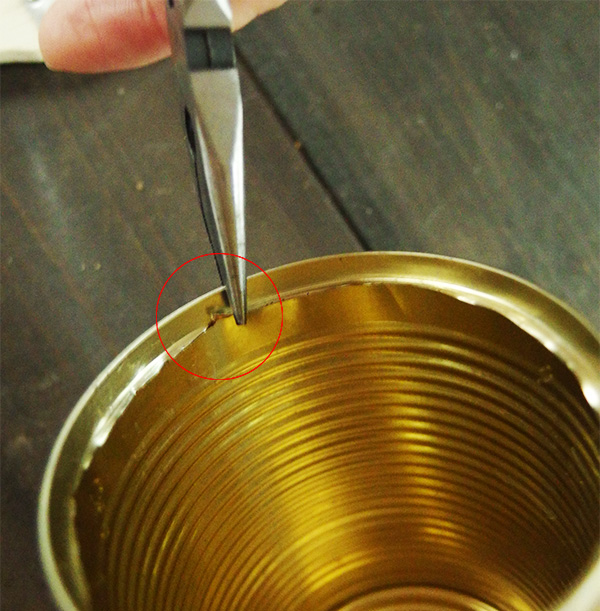 空き缶の蓋を切った縁の部分を怪我しないように処理します。ペンチで縁を内側につぶしていきます。
