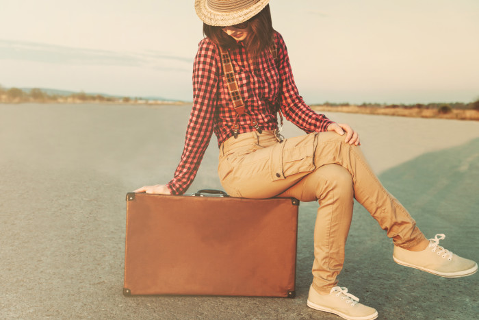 Traveler young woman sitting on vintage suitcase