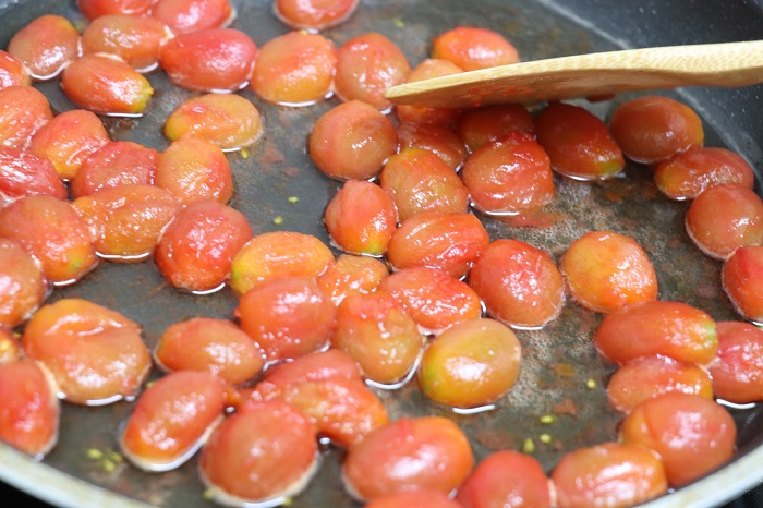 ミニトマトから水分が出てきたら、水分ごとフライパンに移して中火にかけます。