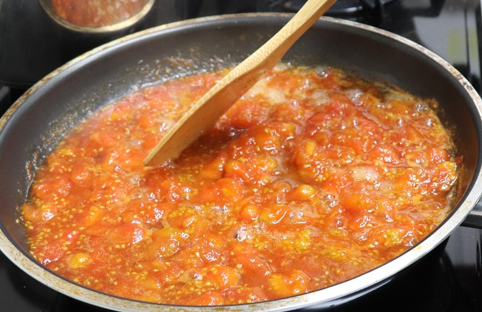 ミニトマトを木べらでつぶしながら煮ます。沸騰してあくが出てきたら取り除きます。