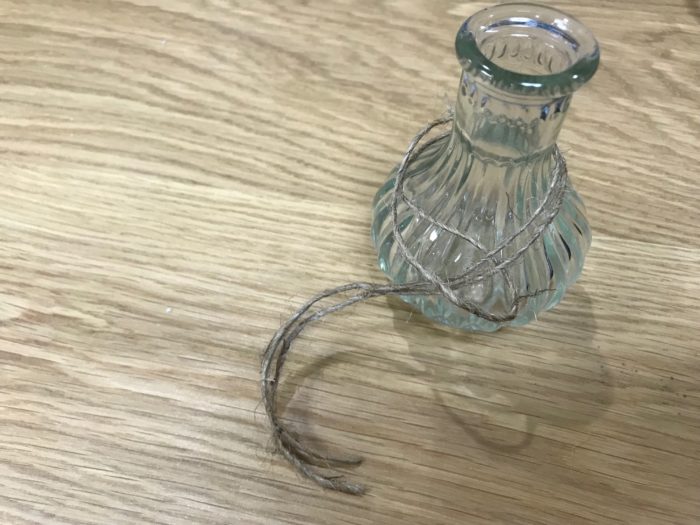 輪にした麻紐を瓶の口に回したら、輪になっている方の端に二つに分かれた片側の麻紐を通します。